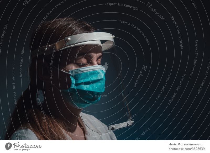 Ärztin mit Gesichtsschutz und Maske, geschlossene Augen, Seitenansicht auf dunklem Hintergrund schwarzer Hintergrund Brasilien Korona-Epidemie Corona-Virus
