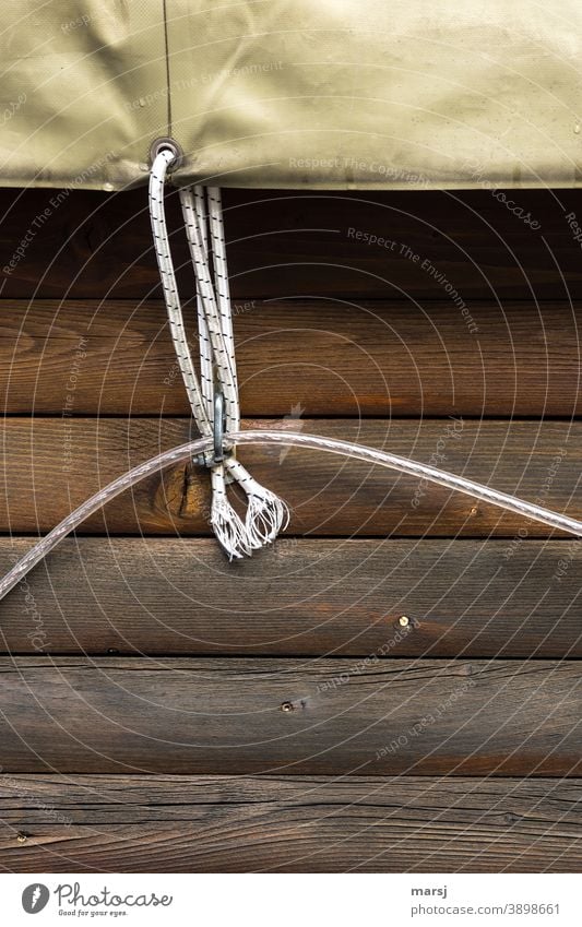 Befestigung mit doppeltem Nutzen. Seil hält die Plane und auch eine Kunststoff-Leuchtschnur Holz Bretterwand Sicherung sichern Schutz Schützen parallel