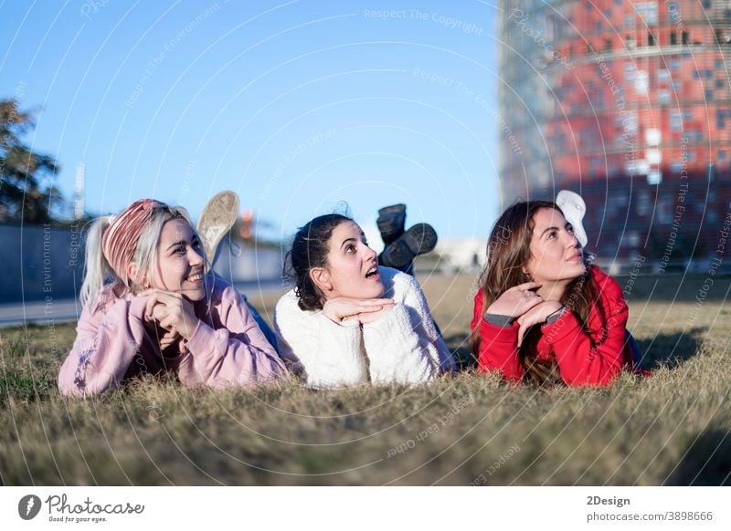 Drei schöne junge Frauen liegen auf dem Rasen, ruhen sich aus und träumen im Park auf dem grünen Gras. Glück Lügen drei Lächeln Freundschaft Boden Freunde