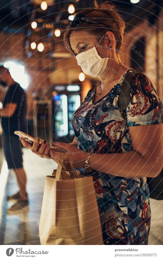 Junge Frau beim Einkaufen im Lebensmittelgeschäft, die die Gesichtsmaske trägt, um eine Virusinfektion zu vermeiden Kaukasier Gespräch covid-19 Lifestyle
