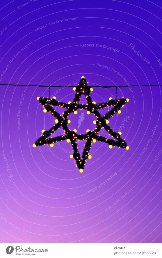 ein grüner Weihnachtsstern leuchtet in der anbrechenden Nacht / Weihnachtsdekoration / Advent Stern leuchten Lampen Glühlampen Leuchtmittel lila blau hängen