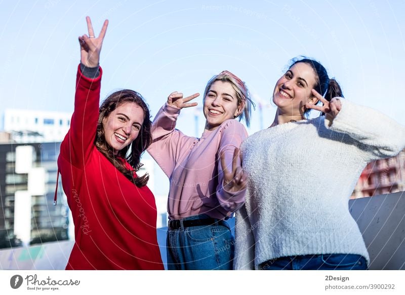 Frontansicht von drei Teenager-Mädchen, die an einem sonnigen Tag im Freien ein Friedenszeichen machen Sieg Zeichen Kaukasier heiter niedlich Ausdruck