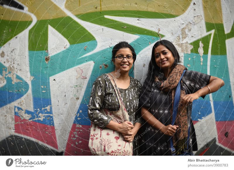 Porträt von zwei indisch-bengalischen brünetten Frauen/Freunden/Schwestern vor einer Graffiti-Wand. Indischer Lebensstil Schauspielerin Erwachsener asiatisch
