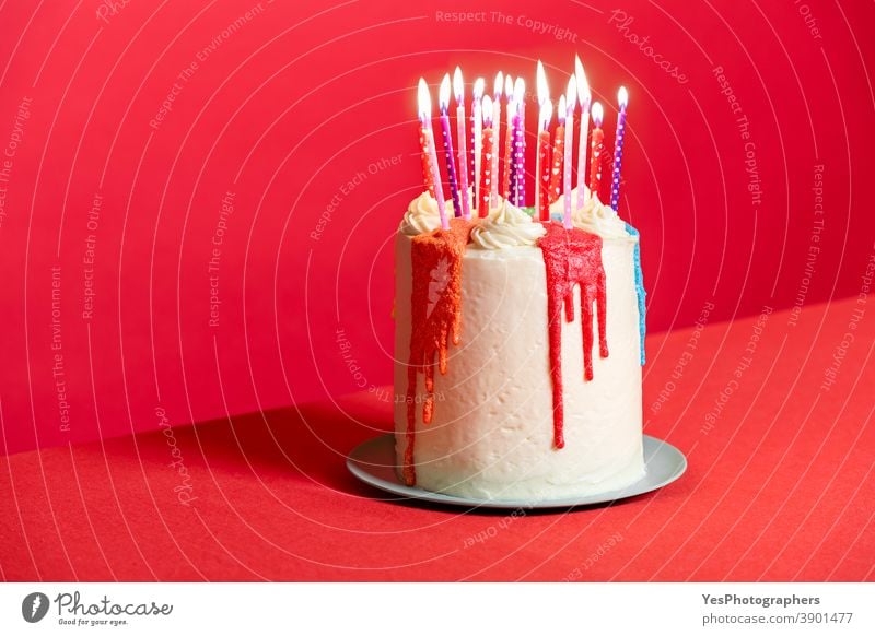 Geburtstagskuchen mit Kerzen auf rotem Hintergrund. Festliche Buttercremetorte Jahrestag Geburtstagstorte Kuchen Kerzenschein zu feiern Feier farbenfroh