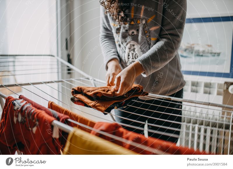 Frau trocknet Wäsche innen Wäscheleine Kleidung Wäscheständer im Innenbereich heimisch häusliches Leben Haus Haushalt Haushaltsführung Mutter Mutterschaft