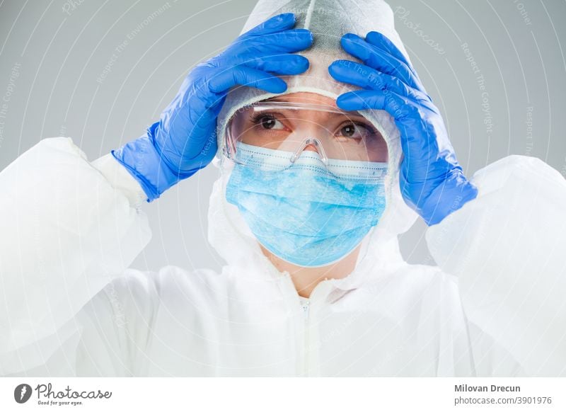 Verzweifelter medizinischer NHS-EMS-Mitarbeiter in weißem Schutzanzug, blauer OP-Maske, Latex-Handschuhe und Schutzbrille, Coronavirus-COVID-19-Pandemie-Krise, die einen Mangel an persönlicher Schutzausrüstung verursacht