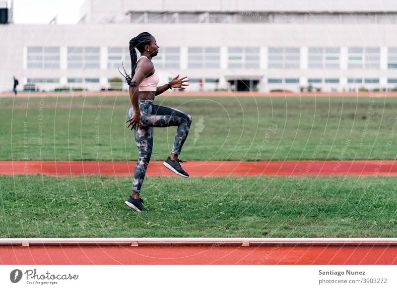 Afrikanisch-amerikanischer Sportler beim Aufwärmen entschlossen muskulös springen Afro-Look Amerikaner Sprinter Beginn Ehrgeiz Motivation Bewegung dynamisch