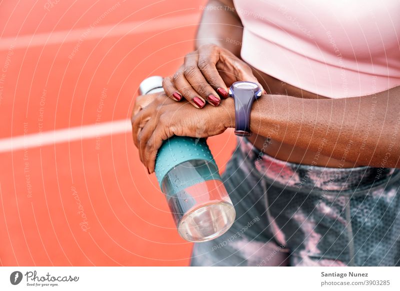 Athlet Sprinter beobachten die Uhr mit einer Flasche Wasser Zeit Start Rennen Training Krawatte Hydratation ethnisch Afro-Look afroamerikanisch Bahn Zug