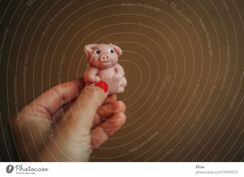 Hand hält kleines Marzipanschweinchen als Glücksbringer für das neue Jahr zu Silvester Schweinchen rosa neues Jahr Glück bringen Glücksschwein Jahreswechsel
