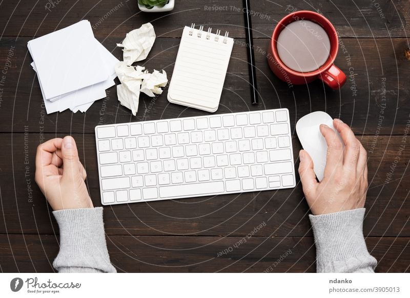 weiße drahtlose Tastatur und Maus auf einem braunen Holztisch, neben einer weißen Tasse mit Kaffee Business Keyboard Büro Computer Arbeitsplatz Kaukasier Hand