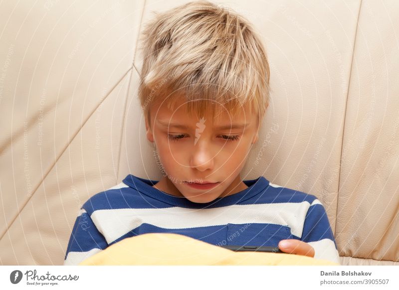 Kleines Kind spielt ein Spiel oder sieht sich etwas auf einem mobilen Smartphone an Bett Schlafenszeit Junge Kaukasier Handy Funktelefon Kindheit Mitteilung