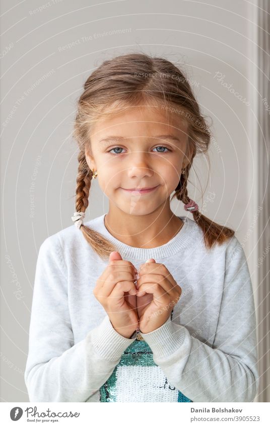 Porträt von niedlichen kleinen Mädchen zeigt Hand Herz Geste, süße kostbare Kind machen Körpersprache, Liebe, positive Gefühl und Emotion bezaubernd Waffen Baby