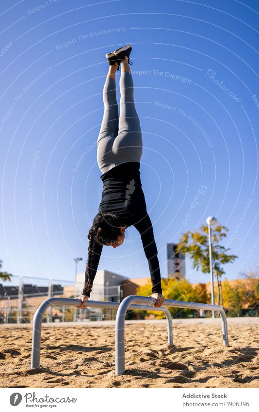 Starke Sportlerin balanciert im Spagat auf dem Barren Handstand Frau Split calisthenics Training Gleichgewicht parallel stark anstrengen Athlet passen üben