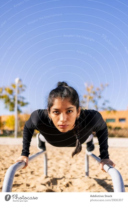 Sportlerin balanciert auf Parallelbarren Frau parallel Bar Training Übung calisthenics gymnastisch akrobatisch Athlet ethnisch üben Konzentration Ausdauer Kraft