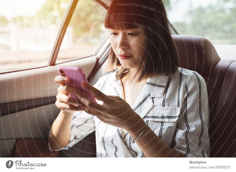 Junge asiatische Fahrgastfrau benutzt ihr Smartphone auf dem Rücksitz eines Autos, Transport- und Lifestyle-Konzept attraktiv Automobil Auto auf dem Rücksitz