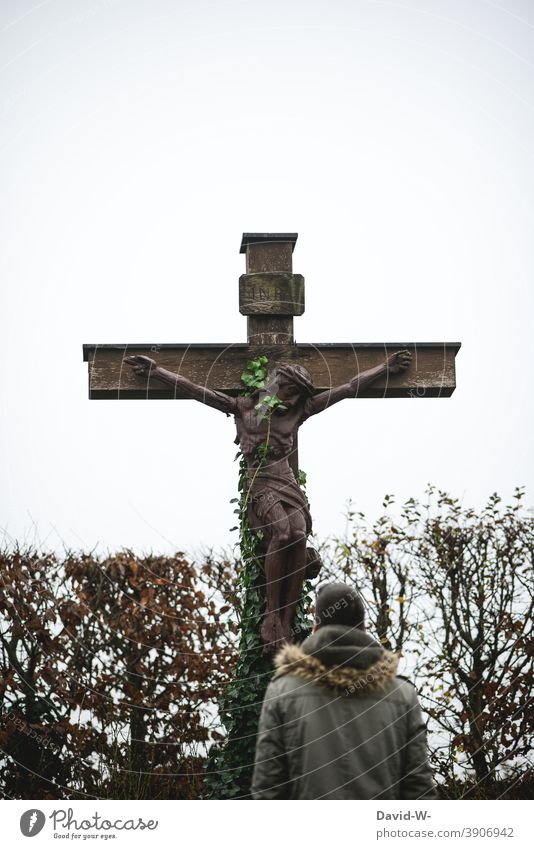 Mann steht vor einem alten Kreuz das von Kletterpflanzen umrankt ist Religion & Glaube Gott Vergessenheit Hoffnung Christliches Kreuz Jesus Christus beten