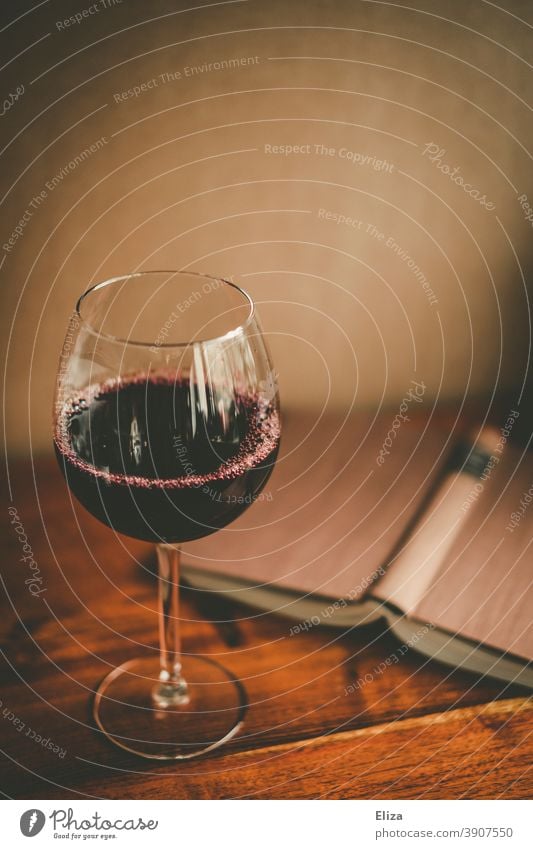 Ein Glas Rotwein und ein aufgeschlagenes Buch. Zeit für sich selber. Wein lesen Weinglas Entspannung Alkohol genießen Rotweinglas