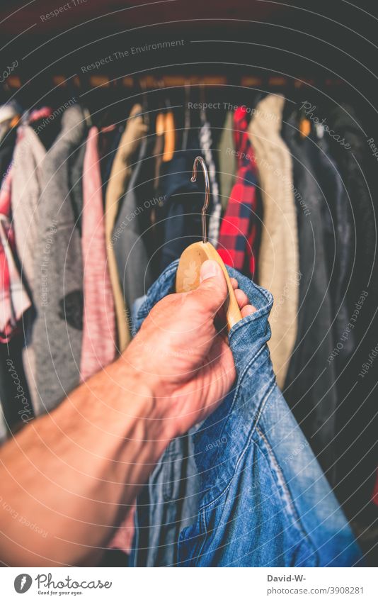 Kleidung aus dem Kleiderschrank nehmen anziehen Entscheidung Hemd Kleiderbügel Konsum greifen Hand Mann Mode Stil