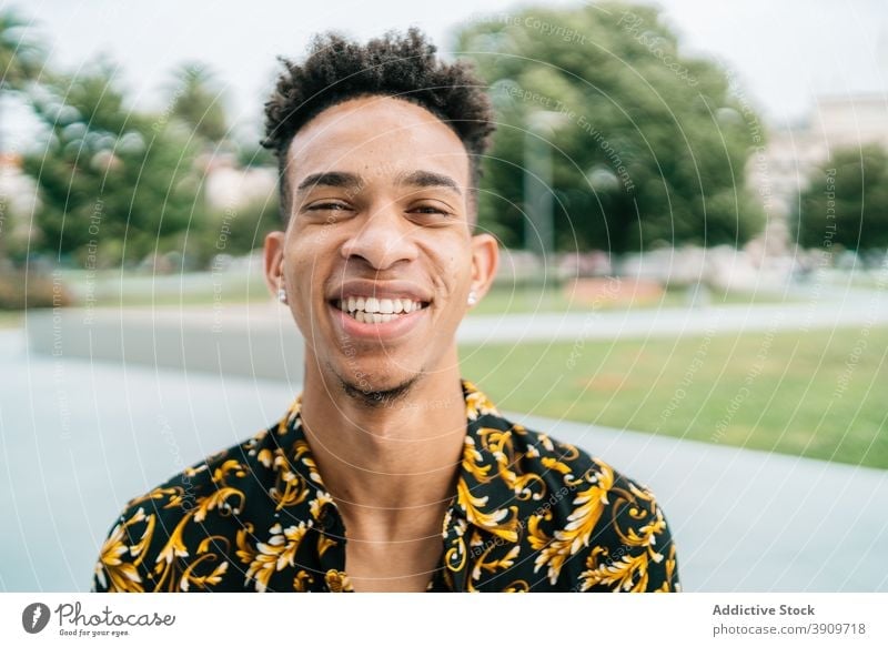 Positiver schwarzer Mann, der in die Kamera lächelt Lächeln trendy gutaussehend Porträt heiter jung Afro-Look Frisur Großstadt männlich ethnisch Afroamerikaner