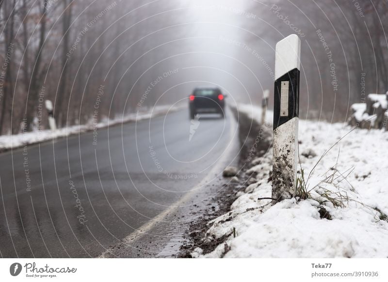 ein Auto, das auf einer nebligen Winterwaldstraße fährt Nebel Auto auf nebliger Straße Auto auf winterlicher Straße PKW Abend Fahrzeugbeleuchtung Auto in Gefahr