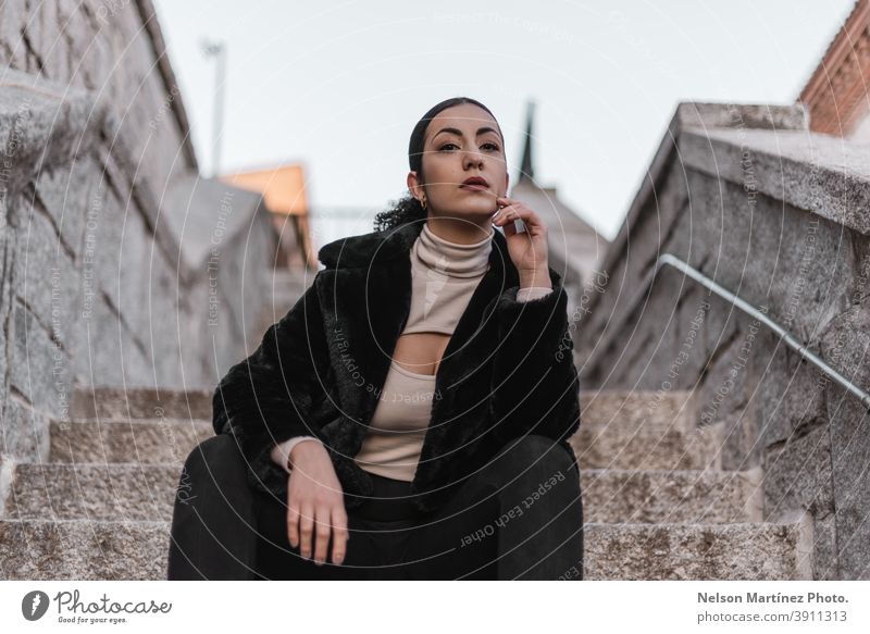 Heiße stilvolle Frau trägt schwarze Kleidung und sitzt auf einer Steintreppe. hübsch Afro-Look attraktiv Ethnizität echte Frau Mensch Textfreiraum Winter Frisur