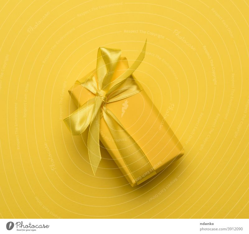rechteckige Schachtel mit einem in gelbes Papier eingewickelten und mit einem gelben Seidenband gebundenen Geschenk festlich Kasten Gruß Feiertag sehr wenige