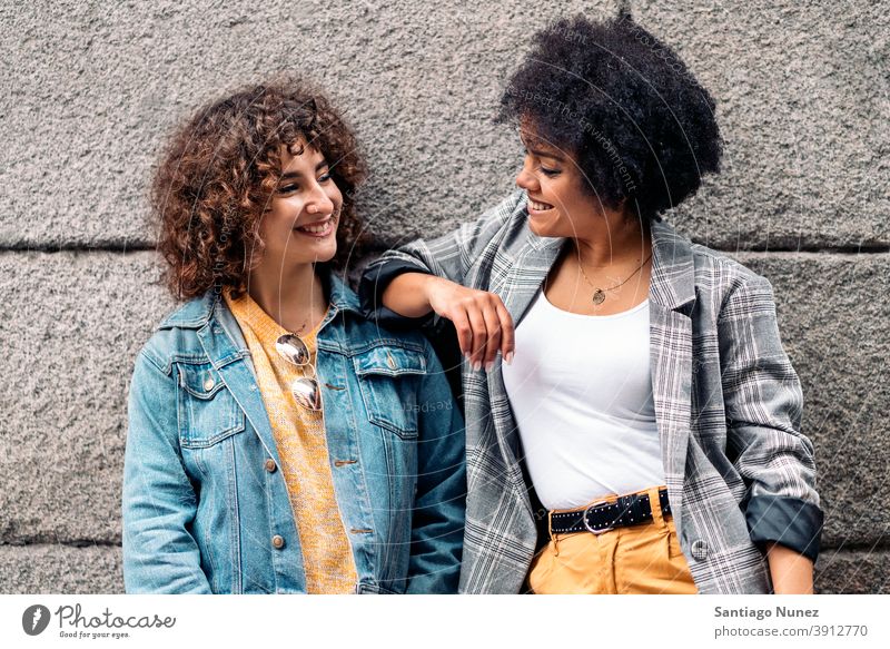 Cool Afro Mädchen und Freund lächelnd Frauen die sich gegenseitig ansehen Straße multiethnisch Afro-Mädchen Kaukasier Porträt Spaß haben Vorderansicht Freunde