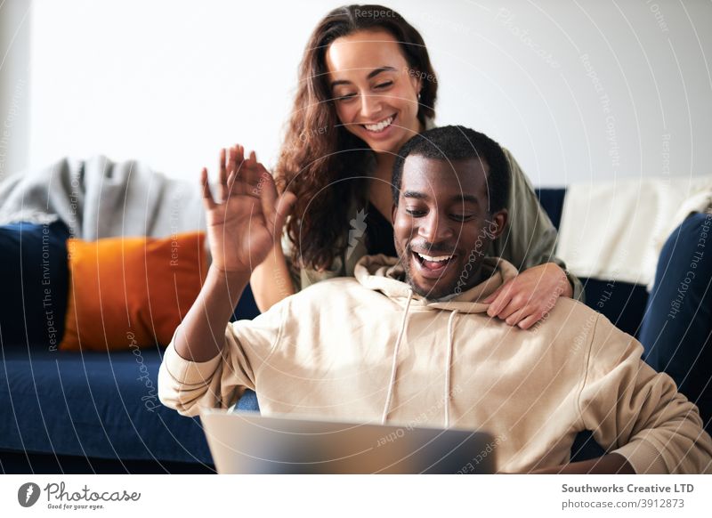 Entspanntes junges Paar zu Hause sitzen auf Sofa machen Videoanruf auf Laptop-Computer Video-Chat Mitteilung winkend Familie Freunde Eltern Sitzen räkeln