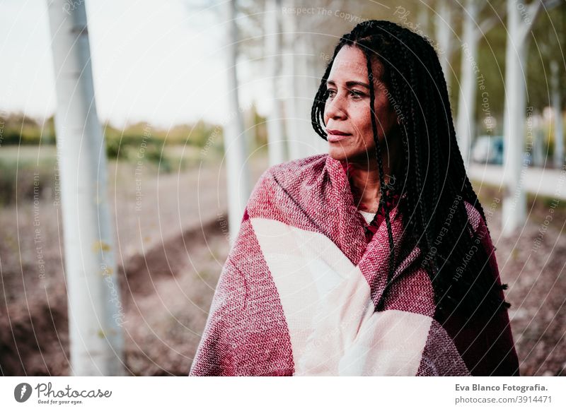 Porträt von hispanischen Mitte erwachsene Frau im Freien halten in Decke eingewickelt. Herbstzeit Afrofrau Latein Sonnenuntergang Natur Hut Lächeln Glück