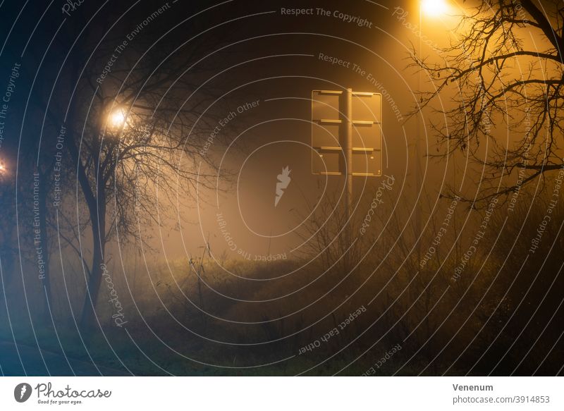 Nebel in den Straßen der Stadt Luckenwalde ,Verkehrsschild von hinten, Straßenlampe hinter einem Baum neblig Nacht Lichtmast Peitschenlaterne Straßenleuchte