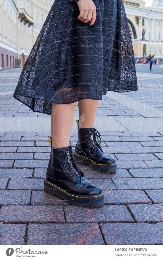 Ein Element der Garderobe einer modischen Frau ist ein schickes schwarzes Kleid und Stiefel. Mädchen Dame im Freien Porträt attraktiv Straße schön jung urban