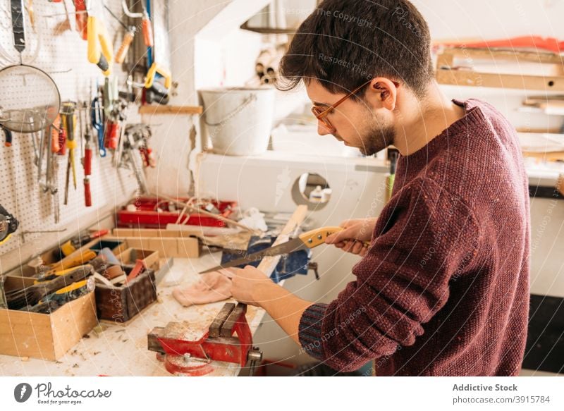 Fokussierter männlicher Schreiner bei der Arbeit mit Holz in der Werkstatt Holzarbeiten Tischlerin Mann Zimmerer geschnitten Schiffsplanken Säge Schreinerei