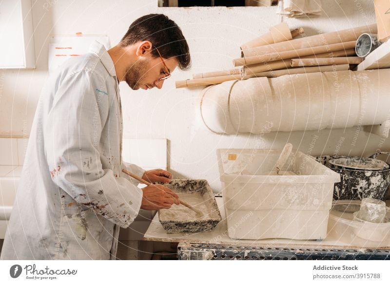 Handwerker bei der Arbeit mit Gips im Kunstatelier Kunstgewerbler verputzen Werkstatt Kunsthandwerker Form eingießen liquide Handarbeit Fähigkeit Mann männlich