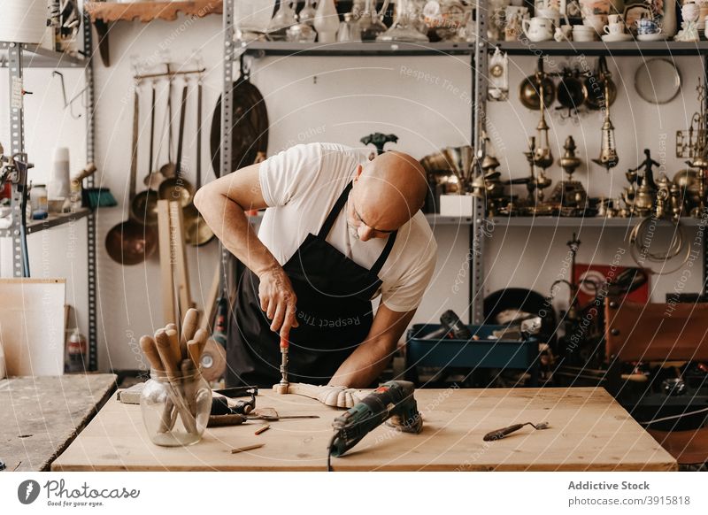 Handwerker schnitzt Holz in der Werkstatt Zimmerer schnitzen Holzarbeiten Beitel Hammer Arbeit kreieren Instrument professionell Werkzeug hölzern Arbeitsplatz