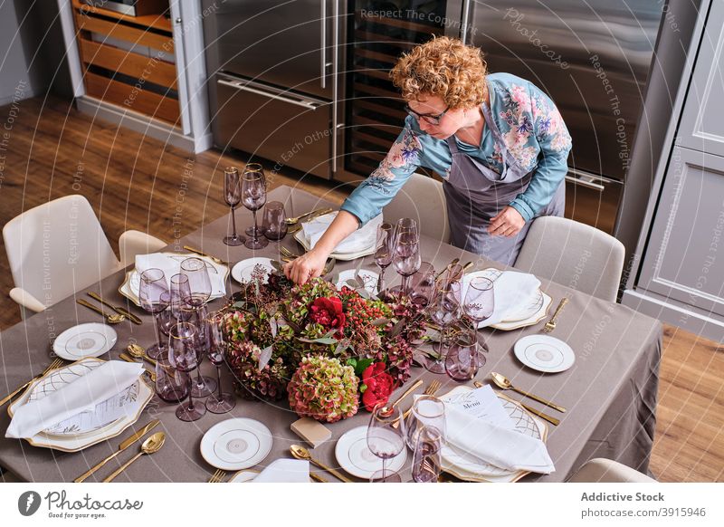 Frau deckt Tisch mit Blumen zu Hause Tabelleneinstellung Einstellung heimwärts festlich Veranstaltung Hausfrau geblümt Dekor Blütezeit filigran Anlass