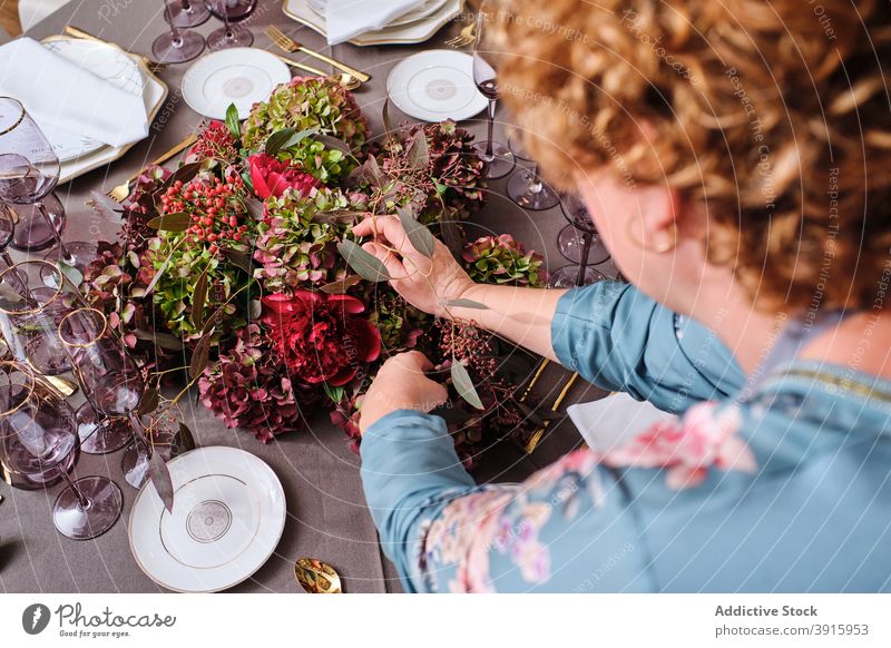 Anonyme Frau deckt Tisch mit Blumen zu Hause Tabelleneinstellung Einstellung heimwärts festlich Veranstaltung Hausfrau geblümt Dekor Blütezeit Anlass