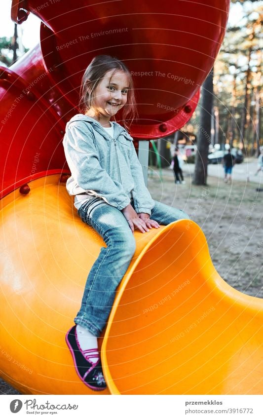 Kleines Mädchen Vorschüler spielen auf einem Spielplatz sitzen auf Rohr Rutsche lächelnd und Blick auf die Kamera positiv freudig Junior Öffentlich Ort