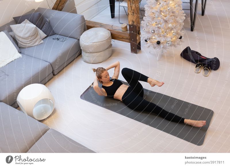 Schöne blonde Frau beim Heimtraining in der Halle. Frau praktiziert Yoga zu Hause. Fitness-Lehrgänge für einen gesunden, aktiven Lebensstil für Mädchen. Frau nutzt Quarantäne für Heimtraining.