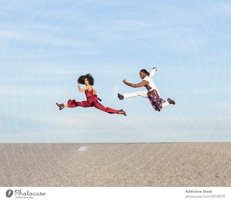 Akrobatisches Paar springt im Sommer über die Straße Tanzen akrobatisch springen trendy ausgefallen ausführen Tänzer Energie Stil Afroamerikaner ethnisch