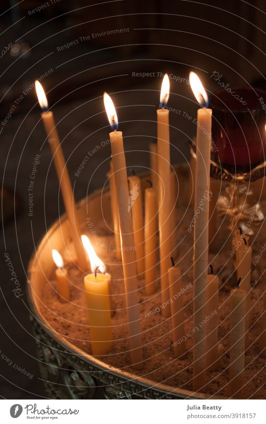 Anzünden von Bienenwachskerzen im Sand; orthodoxe Kirche Kerzen beleuchtet Licht Spitzkerzen zerlaufen Docht Flamme katholisch Gebet beten Kerzenschein Hoffnung