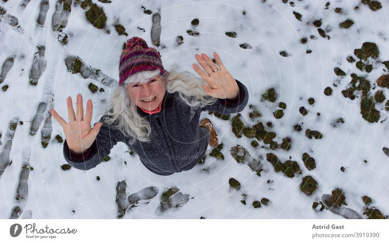 Drohnenaufnahme von einer Frau im Schnee die nach oben winkt frau winter schnee winken lachen luftaufnahme drohnenaufnahme drohnenansicht lustig spaß freuen