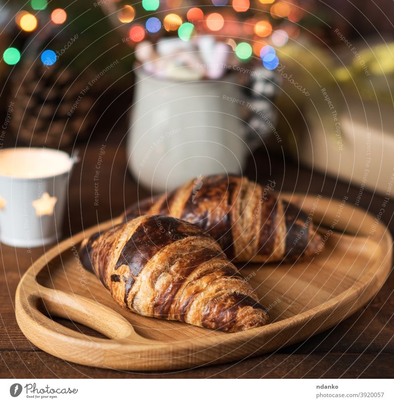 gebackene Croissants und eine weiße Keramiktasse mit Kaffee, hinter den brennenden Weihnachtslichtern Tasse Becher Neujahr Gebäck rollen rustikal Snack süß