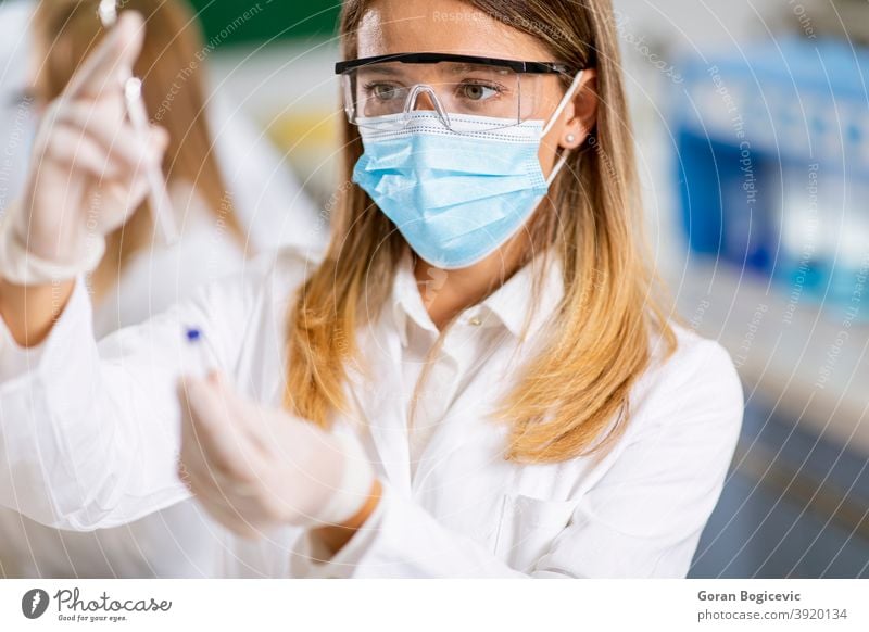 Frau Arzt trägt Schutzmaske im Labor halten Nadel Spritze und Medizin Fläschchen Impfstoff Flasche medizinisch Medikament Wissenschaft Pflege Impfung