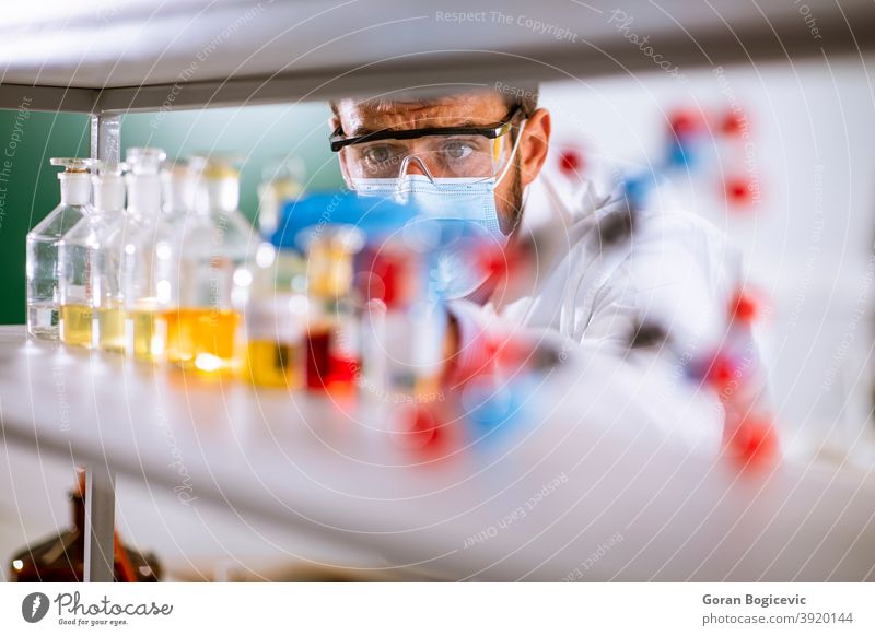 Junger Forscher mit Schutzbrille beim Prüfen von Reagenzgläsern Bildung Labor forschen Experiment Wissenschaft männlich Wissenschaftler wissenschaftlich Mann
