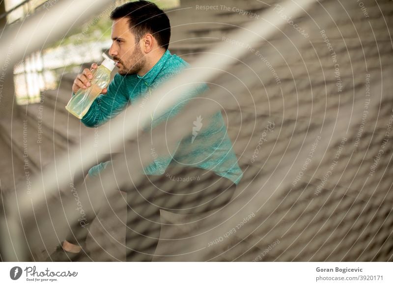 Junger Mann ruht sich während des Trainings mit einer Flasche Wasser aus Fitness männlich jung urban Sport passen Athlet aktiv sportlich Großstadt Gesundheit