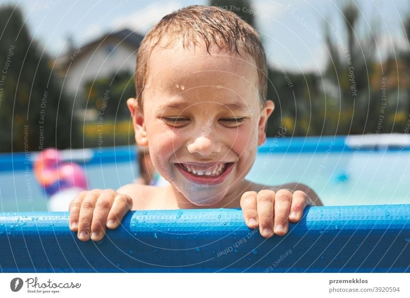 Porträt eines glücklich lächelnden Jungen, der an einem sonnigen Sommertag im Schwimmbad spielt und Spaß hat authentisch Hinterhof Kindheit Kinder Familie