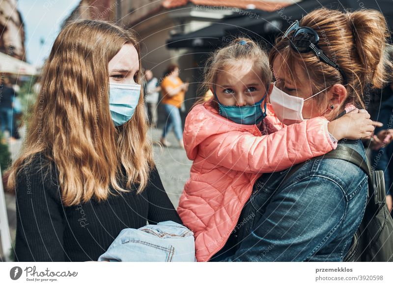 Familienmutter und ihre Töchter stehen in einer Straße in der Innenstadt und tragen die Gesichtsmasken, um eine Virusinfektion zu vermeiden Anruf Pflege