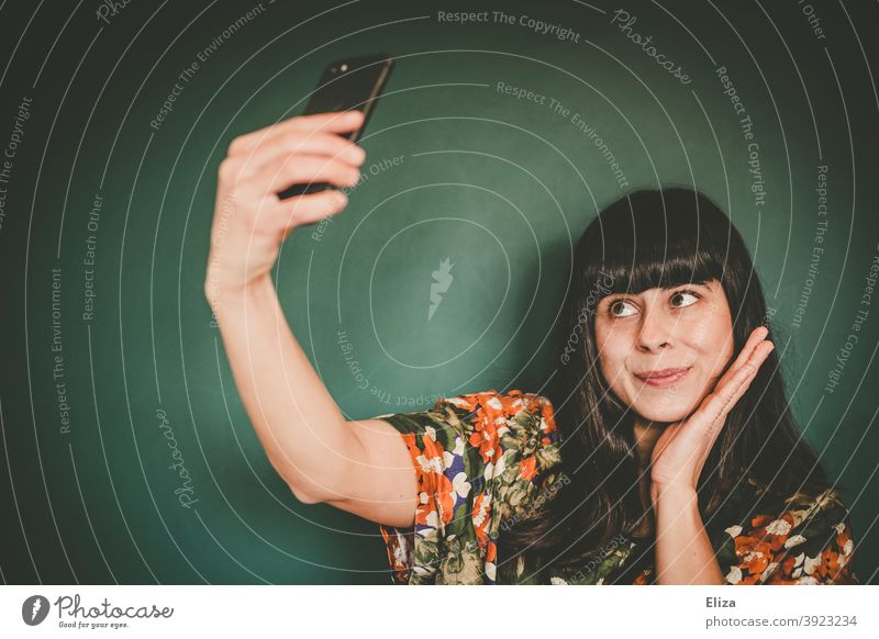 Junge Frau macht ein Selfie mit ihrem Smartphone junge Frau Eitelkeit selbstverliebt Selbstportrait Influencerin Handy Telefon Gesicht brünett braunhaarig