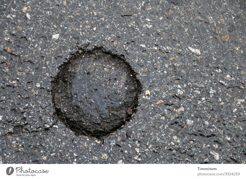 Ein schwer zu deutendes Zeichen auf der Straße Asphalt Vertiefung kreisrund rätselhaft nass Symbol Außenaufnahme Menschenleer Farbfoto