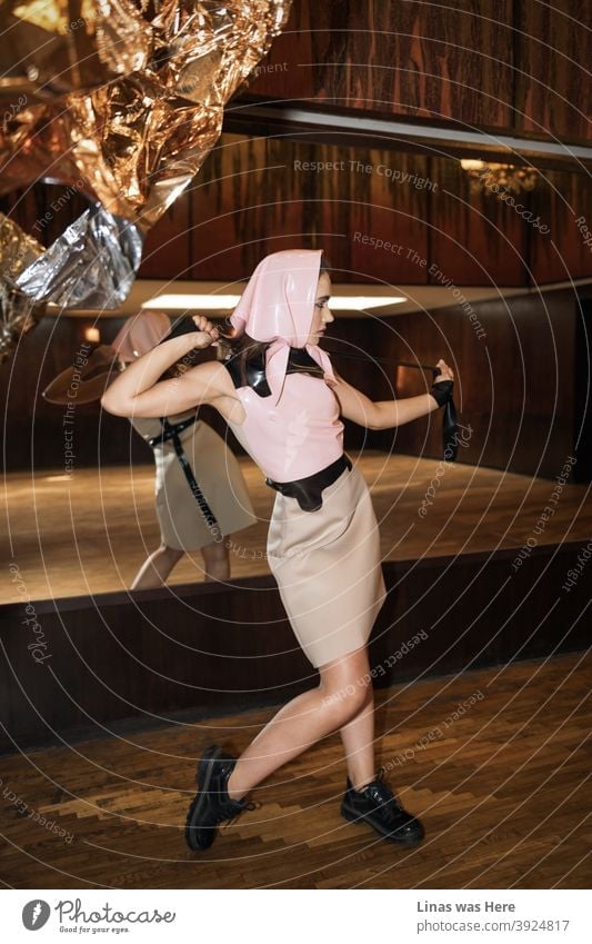 Ein Modeshooting für eine Latexbekleidungsmarke mit einem schönen, in Rosa gekleideten Model. Die Retro-Vintage-Holz-Hintergrund ist eine schöne Übereinstimmung für diese.